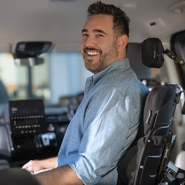 Man using a wheelchair smiling inside an adapted vehicle during a driving assessment with Drive On Therapy.