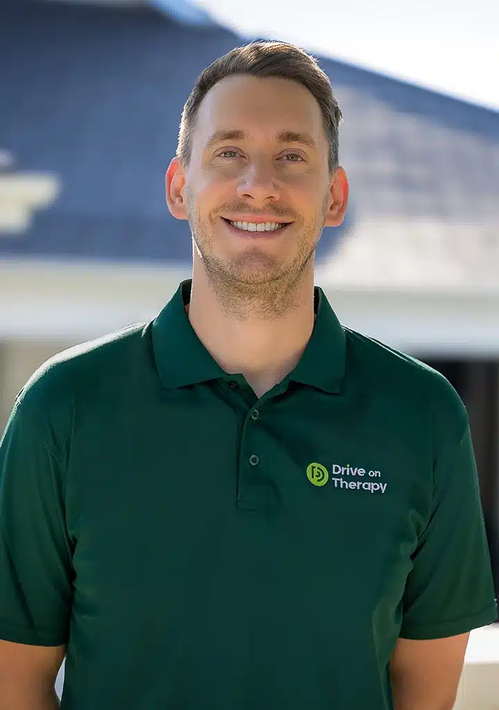Drive On Therapy occupational therapist wearing a branded green polo shirt, smiling outdoors.