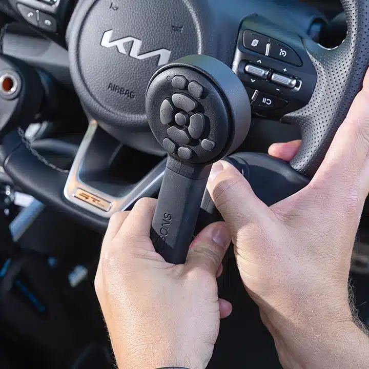 Close-up of a hand using a spinner knob with integrated secondary controls on a Kia steering wheel.