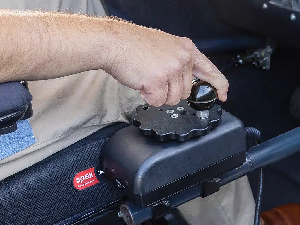 Close-up of a hand operating a mini wheel controller for adaptive driving.