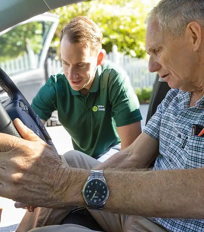 Occupational therapist supporting older client during adaptive driving rehabilitation session inside a modified vehicle.