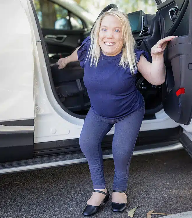 Woman with short stature confidently entering a modified vehicle, exploring her potential to drive independently.