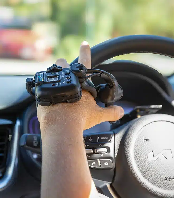 Close-up of a hand operating advanced vehicle modification system during an occupational therapy driving assessment.