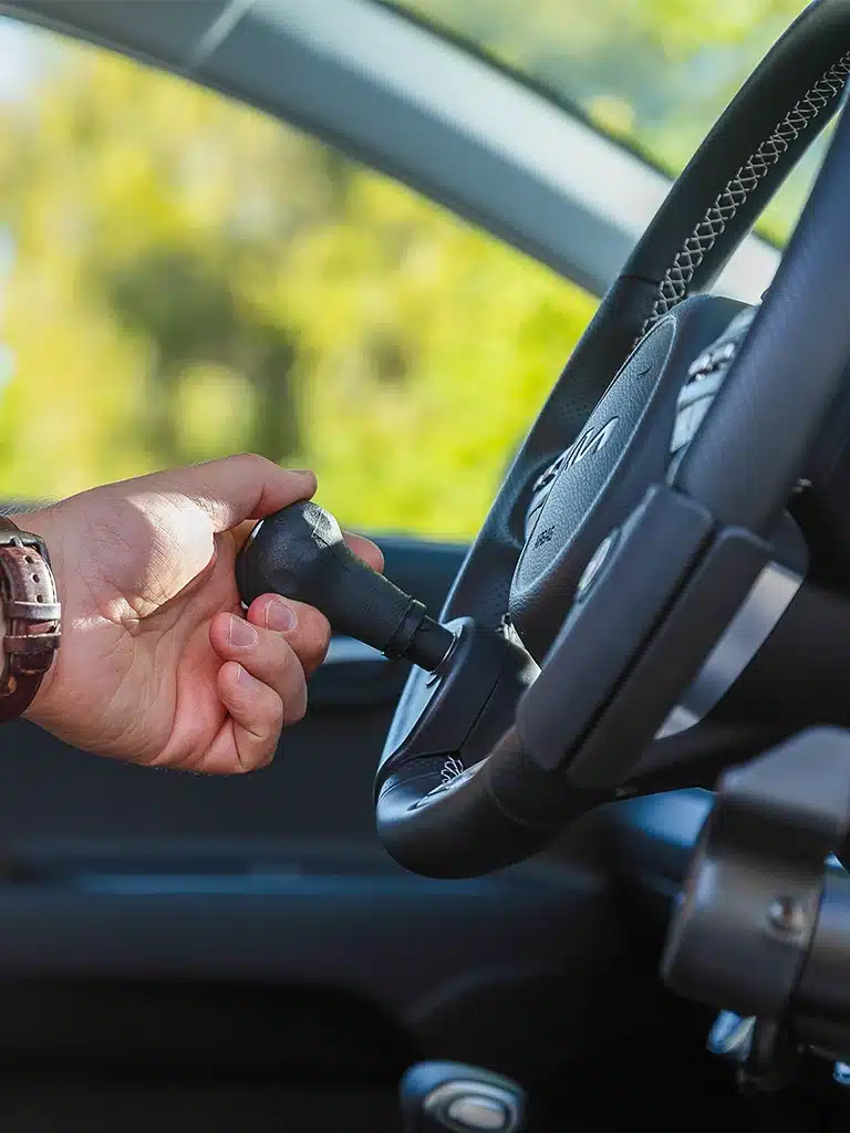 Close-up of hand operating an ergonomic spinner knob installed on an adaptive steering wheel.