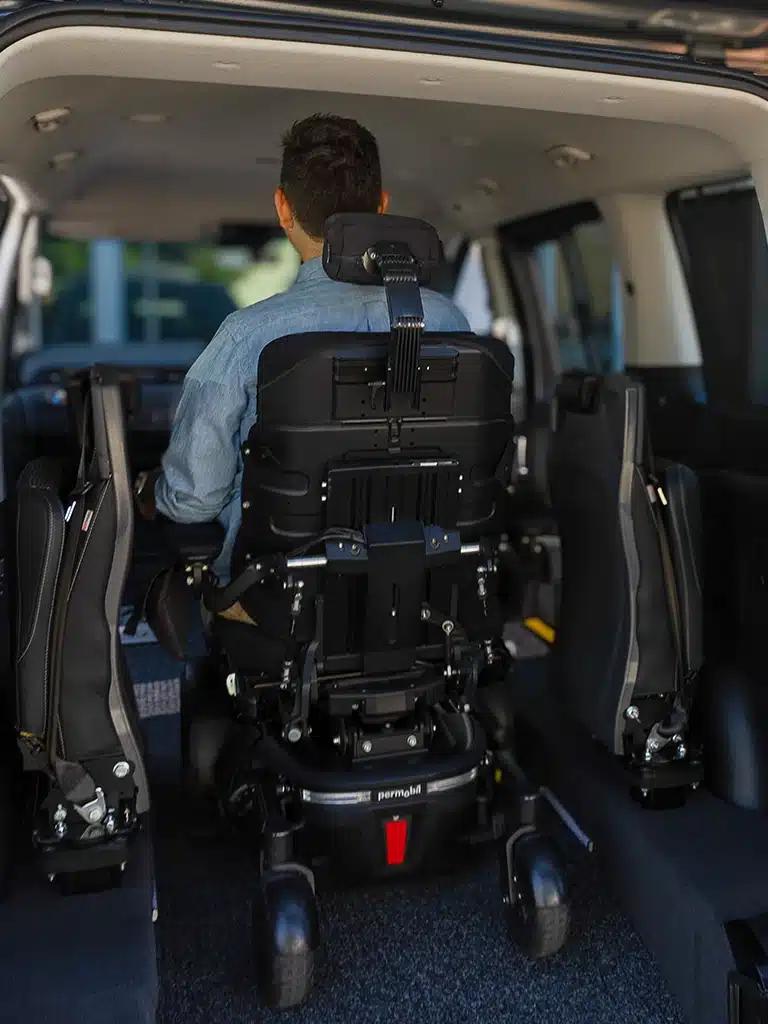 View from inside a wheelchair accessible van showing man secured in place as seated driver.
