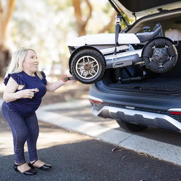 Woman unloading a mobility scooter from the back of an SUV, demonstrating community access and vehicle transport solutions.