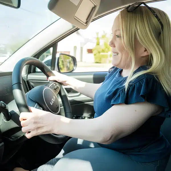 Woman driving through NDIS-funded specialised driver training using adaptive vehicle controls.