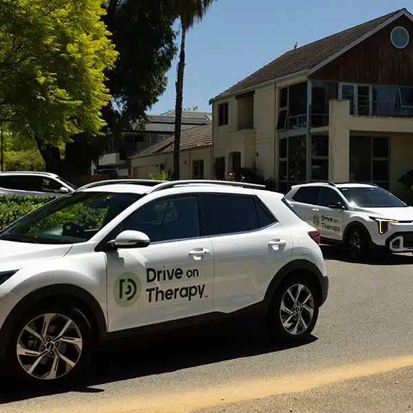 Two Drive on Therapy vehicles parked outside a residential property before a P-Drive driving assessment session.