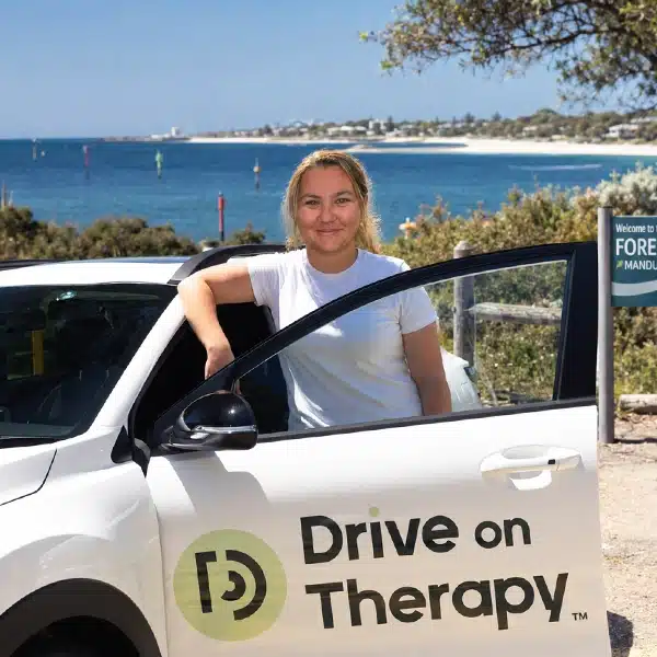 Chloe from Drive on Therapy standing beside a branded company vehicle near Mandurah Foreshore, Western Australia.