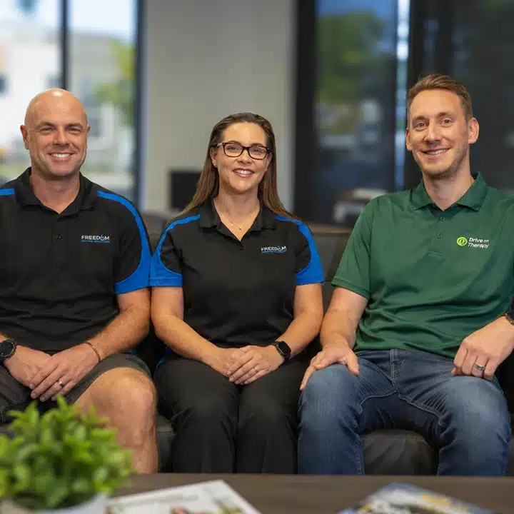 Team members from Drive on Therapy and Freedom Motors standing together indoors, smiling at the camera.
